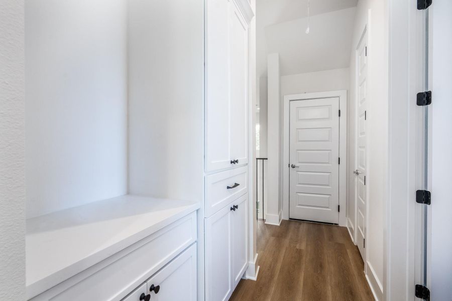 Bright hallway with built-in cabinetry, black hardware, and warm vinyl floors offering a clean and modern flow. Bright hallway with built-in cabinetry, black hardware, and warm vinyl floors offering a clean and modern flow.
