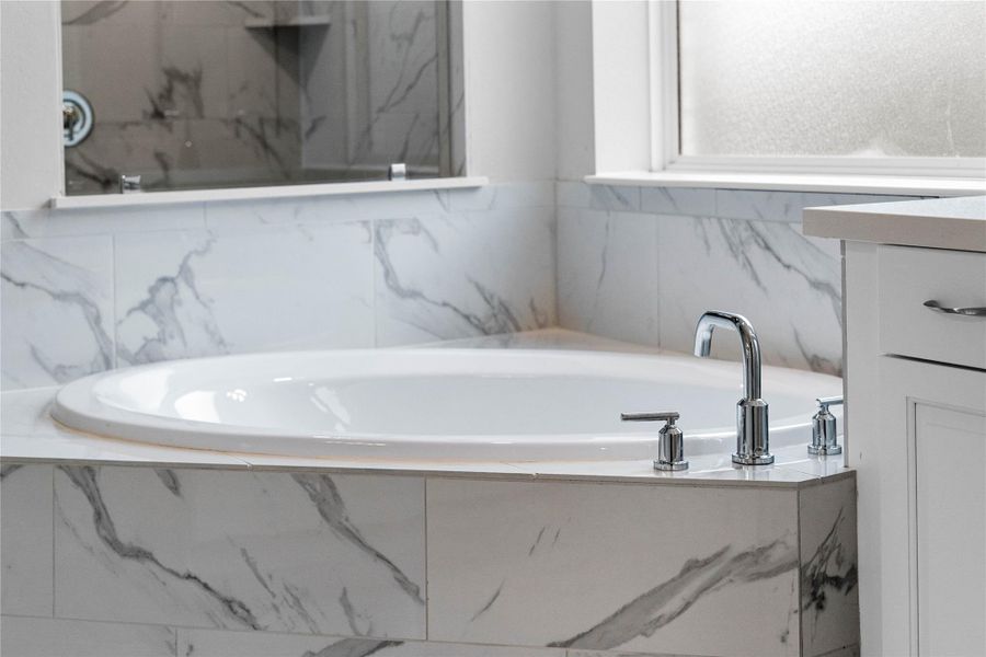 Unwind after a long day in the deep, corner soaking tub, a perfect sanctuary for relaxation. The tub is accented by stylish fixtures. Unwind after a long day in the deep, corner soaking tub, a perfect sanctuary for relaxation. The tub is accented by stylish fixtures.