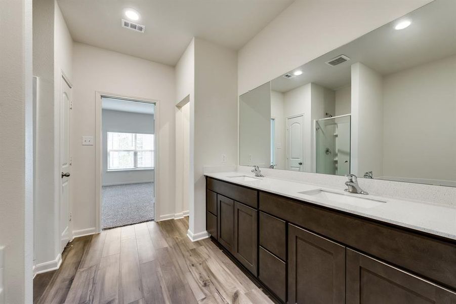 Bathroom with a shower with door, wood-type flooring, and double sink vanity