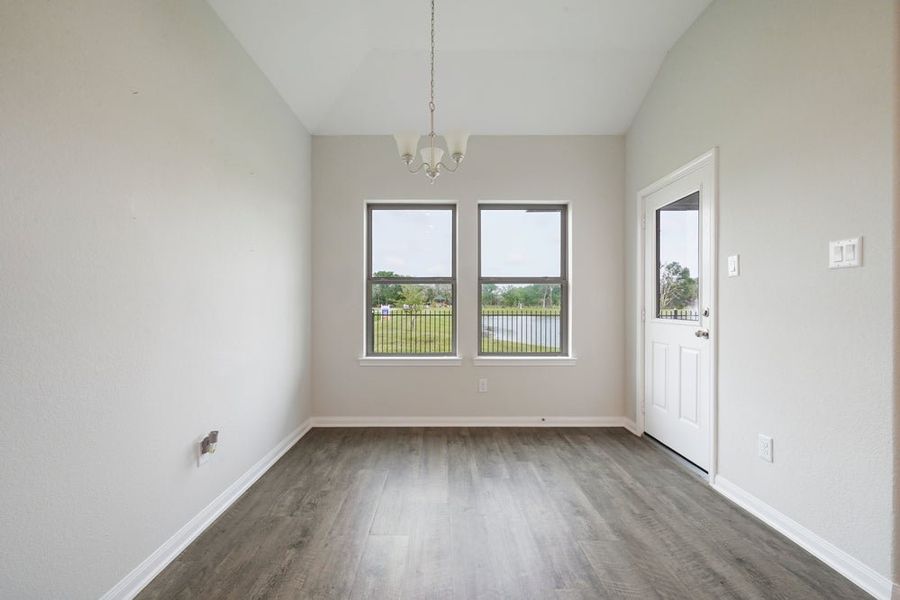 Empty dining area with hardwood floors, chandelier, two windows, and exterior door with yard view Empty dining area with hardwood floors, chandelier, two windows, and exterior door with yard view