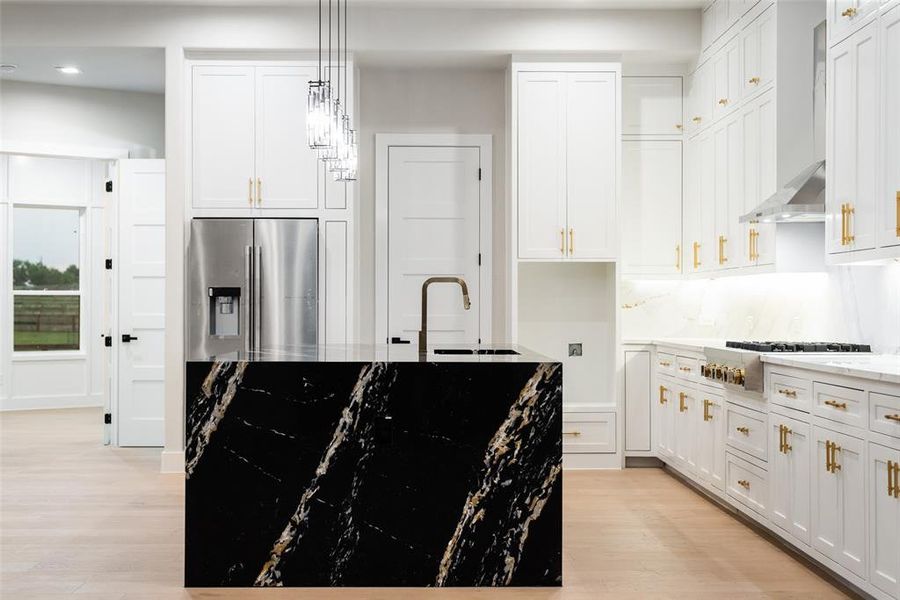 Kitchen with stainless steel appliances, wall chimney exhaust hood, light wood finished floors, recessed lighting, and a sink Kitchen with stainless steel appliances, wall chimney exhaust hood, light wood finished floors, recessed lighting, and a sink