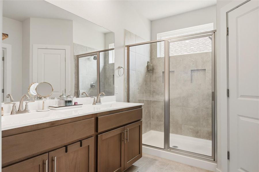 Full bath featuring double vanity, a stall shower, and light tile patterned floors