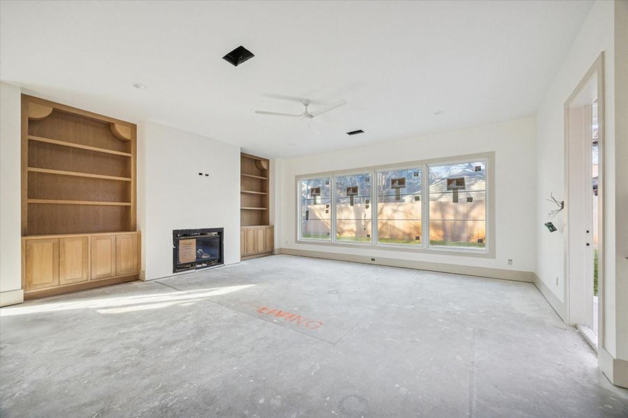 LIVING ROOM - A wide wall of windows draws natural light deep into the space, creating a strong connection to the backyard and enhancing the room’s sense of scale. Custom millwork, warm wood tones, and a balanced layout allow flexibility for multiple seating arrangements or future built ins.