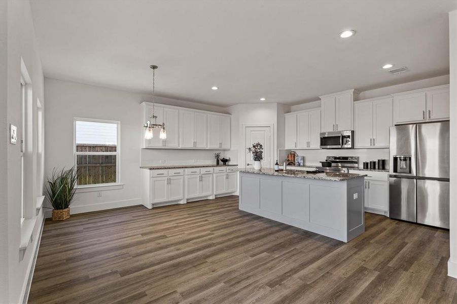 Kitchen with white cabinets, decorative light fixtures, dark hardwood / wood-style flooring, and stainless steel appliances