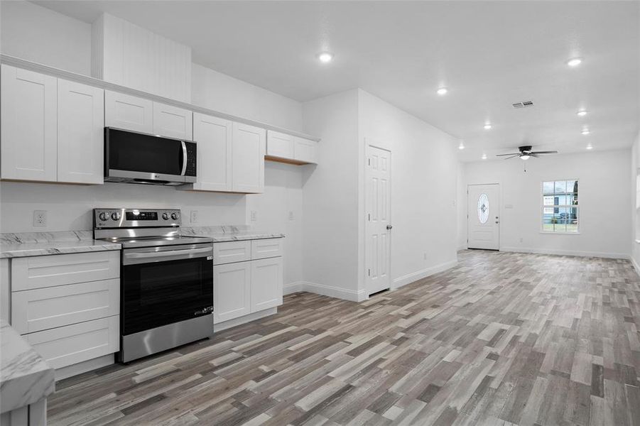 Kitchen with stainless steel appliances, ceiling fan, white cabinets, and recessed lighting