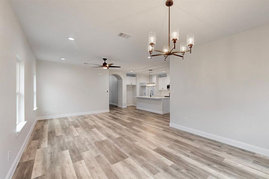 Unfurnished living room featuring ceiling fan with notable chandelier, sink, and light hardwood / wood-style floors