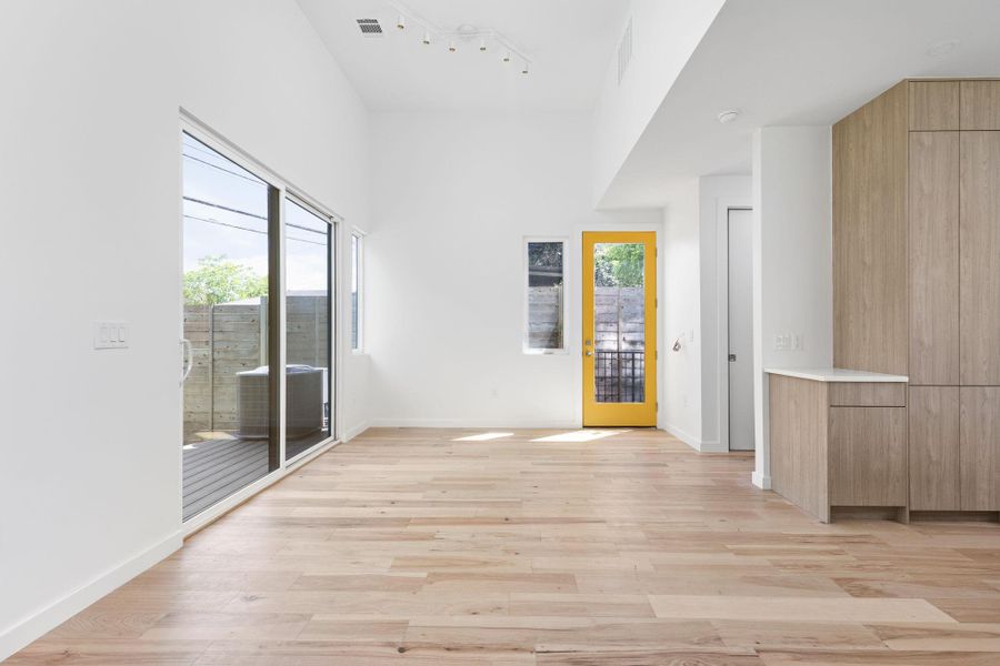 Empty room featuring healthy amount of natural light, light wood-style flooring, and track lighting