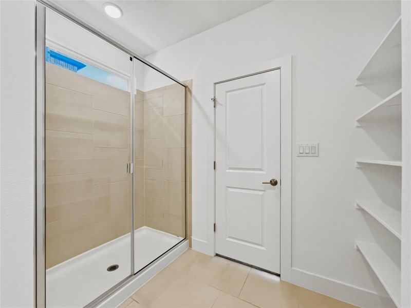 Bathroom featuring a shower stall and light tile patterned flooring