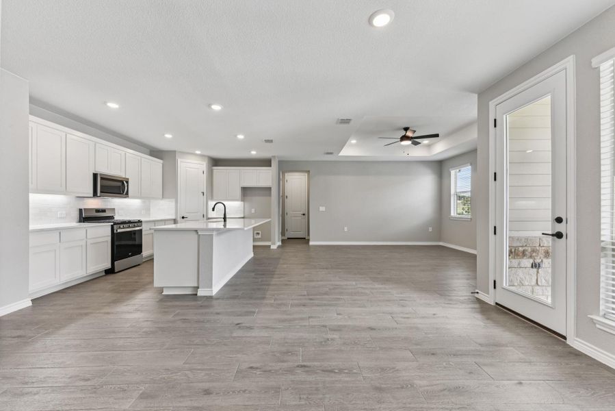 Kitchen featuring stainless steel appliances, white cabinets, a center island with sink, recessed lighting, and light wood-style flooring Kitchen featuring stainless steel appliances, white cabinets, a center island with sink, recessed lighting, and light wood-style flooring