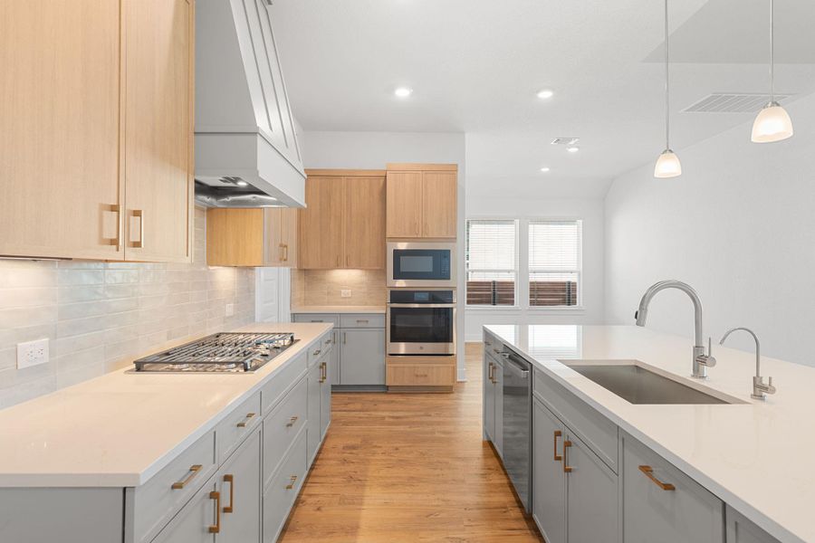 A well-lit kitchen with natural wood cabinetry and a large island creates a contemporary and inviting atmosphere.
