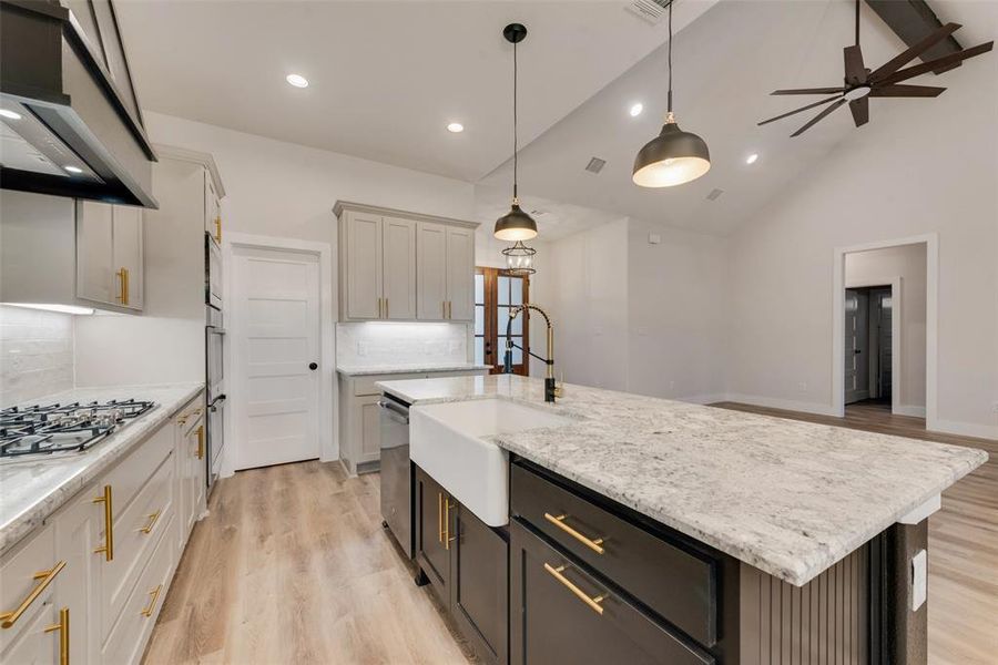 Kitchen with light wood-type flooring, decorative light fixtures, decorative backsplash, ventilation hood, and recessed lighting Kitchen with light wood-type flooring, decorative light fixtures, decorative backsplash, ventilation hood, and recessed lighting