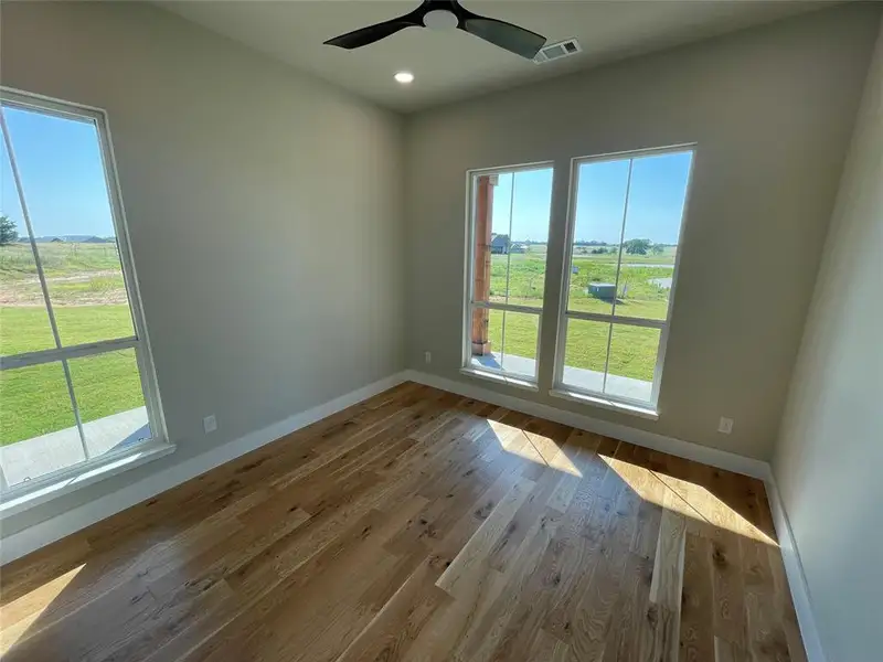 Room with wood-finish flooring, light-toned walls, and multiple large windows