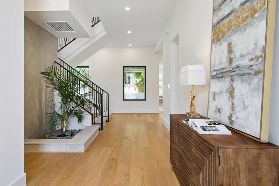 Elegant foyer with iron railing staircase and indoor garden feature. Elegant foyer with iron railing staircase and indoor garden feature.