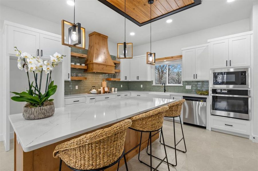 Kitchen with white cabinetry, hanging light fixtures, black appliances, and open shelves