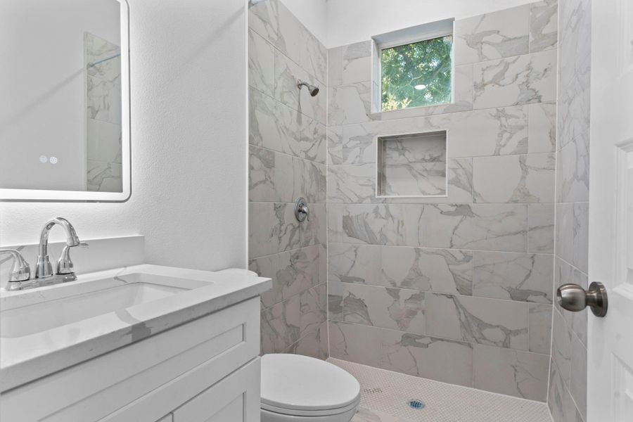 Sleek bathroom with a frameless walk-in shower and LED-lit mirror. Sleek bathroom with a frameless walk-in shower and LED-lit mirror.