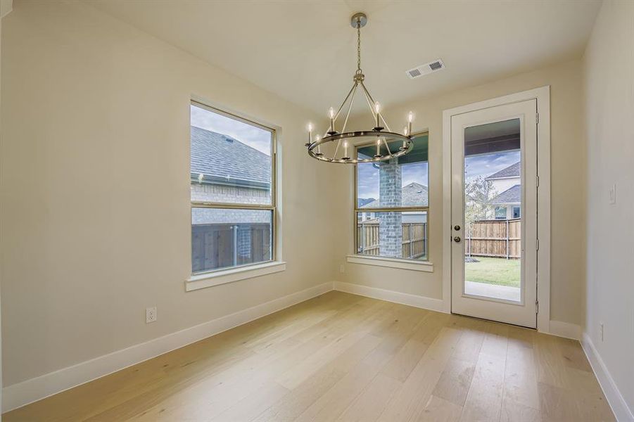 Unfurnished dining area featuring light wood-type flooring and a chandelier Unfurnished dining area featuring light wood-type flooring and a chandelier