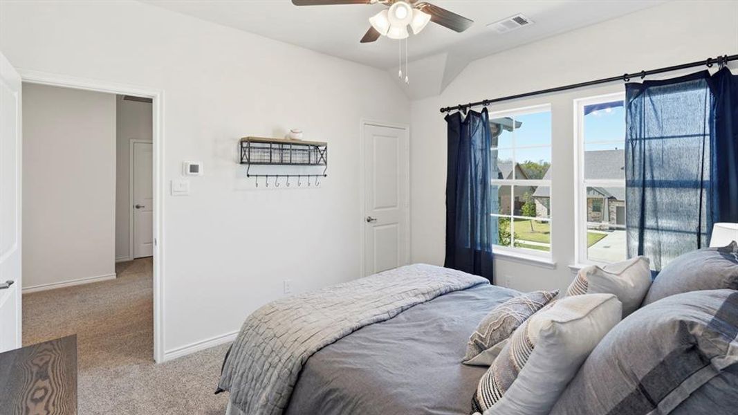 Vaulted ceilings with a ceiling fan, dual windows, plush carpeting, and light-toned wall finishes Vaulted ceilings with a ceiling fan, dual windows, plush carpeting, and light-toned wall finishes