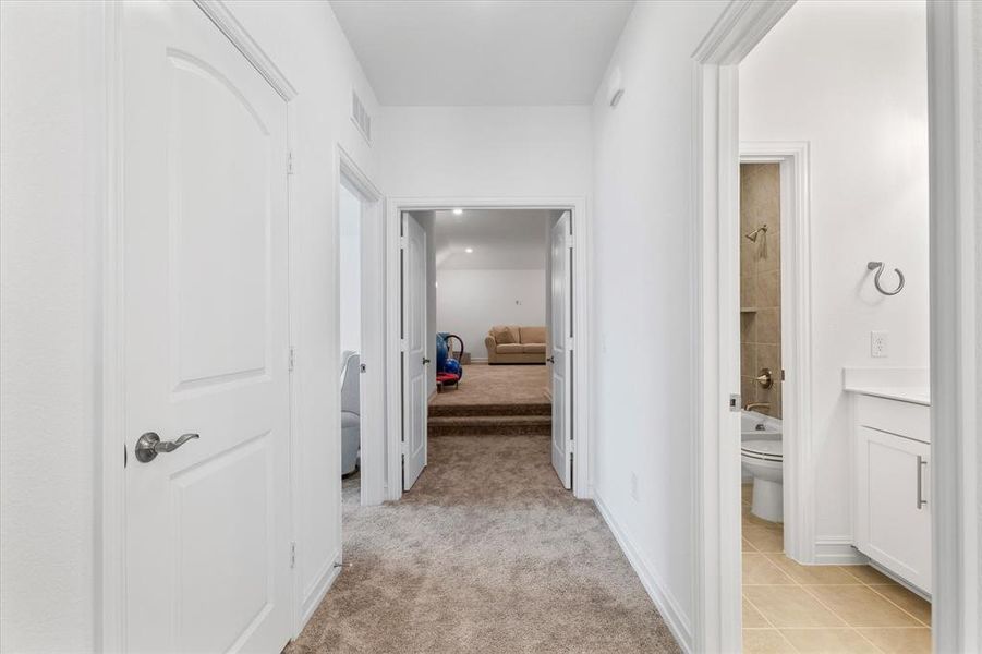 Hall featuring light colored carpet and light tile patterned flooring