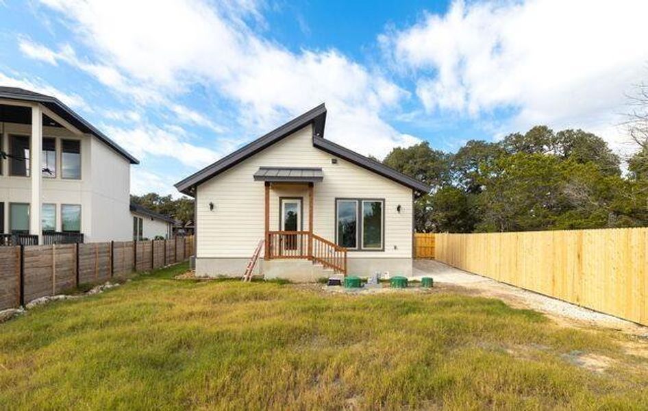 Contemporary single-story residence with light-colored siding, a dark-pitched roofline, and a wood-toned entry porch
