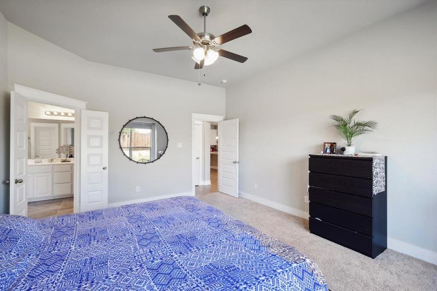 Carpeted bedroom with ensuite bath, sink, and ceiling fan