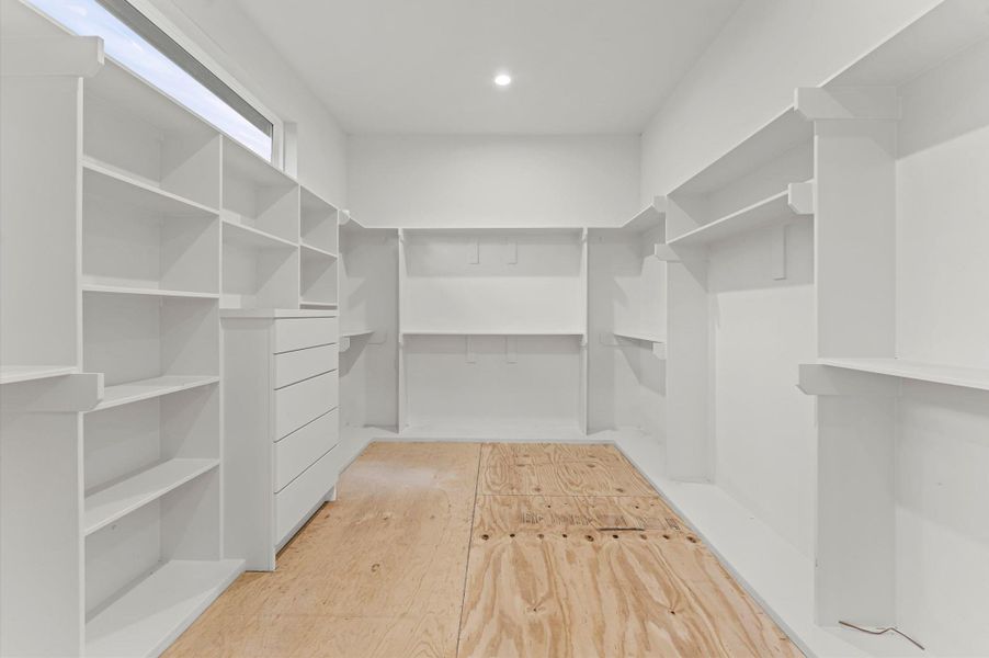 Oversized primary closet with built in chest of drawers.