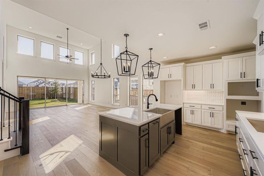 Kitchen featuring white cabinetry, a center island with sink, tasteful backsplash, recessed lighting, and light wood-style floors