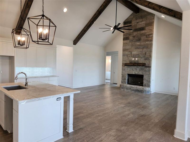 Kitchen featuring beamed ceiling, white cabinets, an island with sink, and wood-type flooring