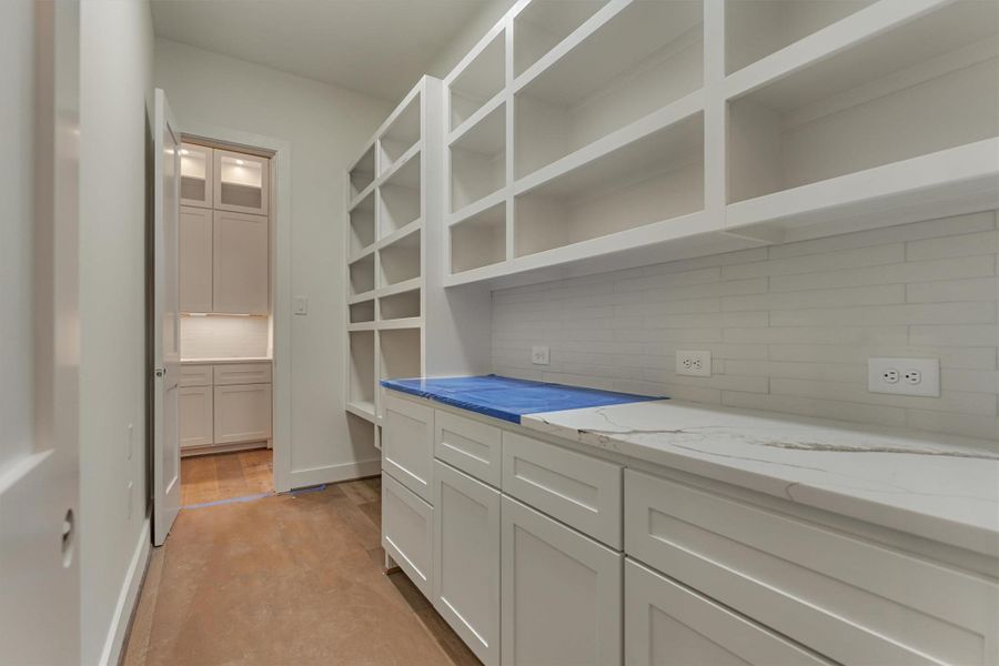 Stunning view from the kitchen showcasing the expansive waterfall island, custom cabinetry, stainless steel appliances, and vaulted living room with a modern shiplap fireplace.