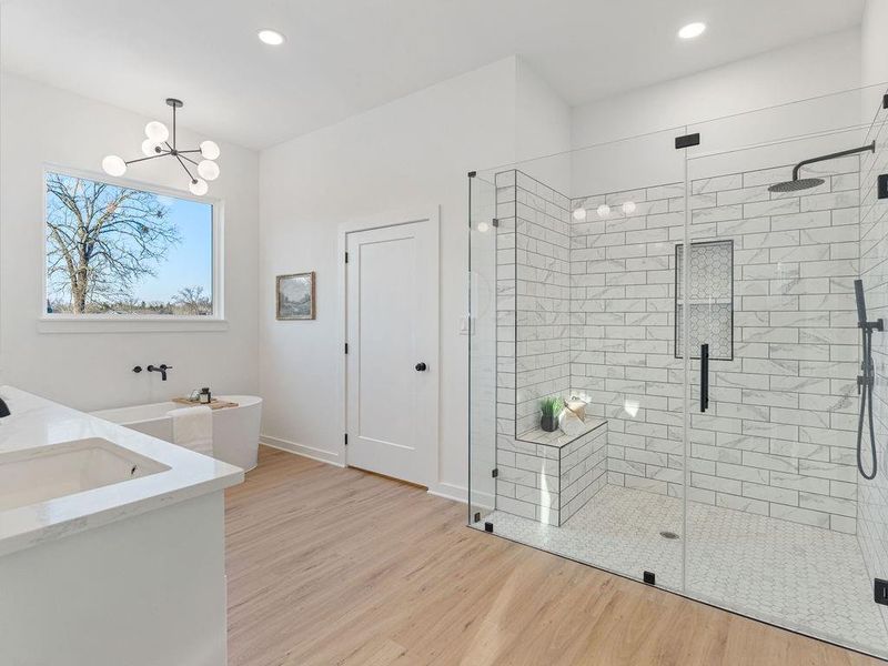 Full bathroom featuring double vanity, light wood-style floors, a shower stall, a chandelier, and a tub