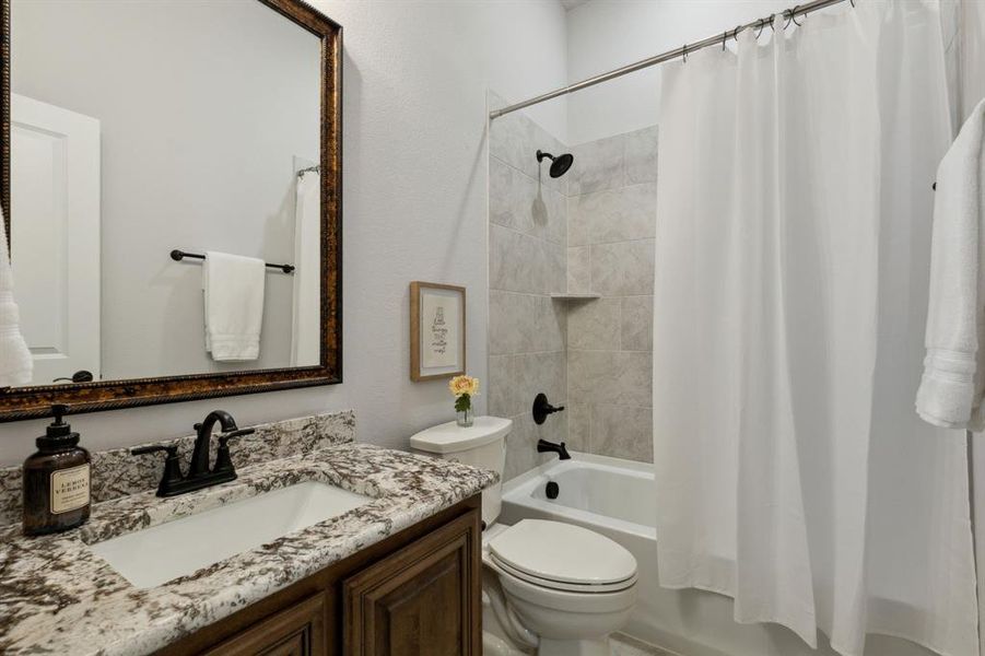 Secondary Bathroom with granite counter tops, designer mirror and lighting, beautiful hardware and tile flooring.