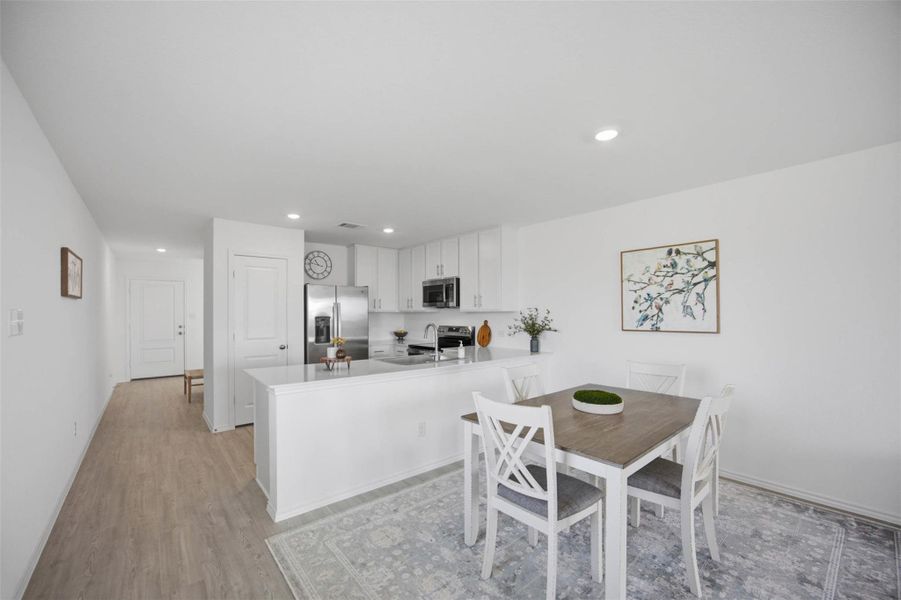 Gleaming luxury vinyl  floors anchor this open concept dining space flowing directly into the kitchen.