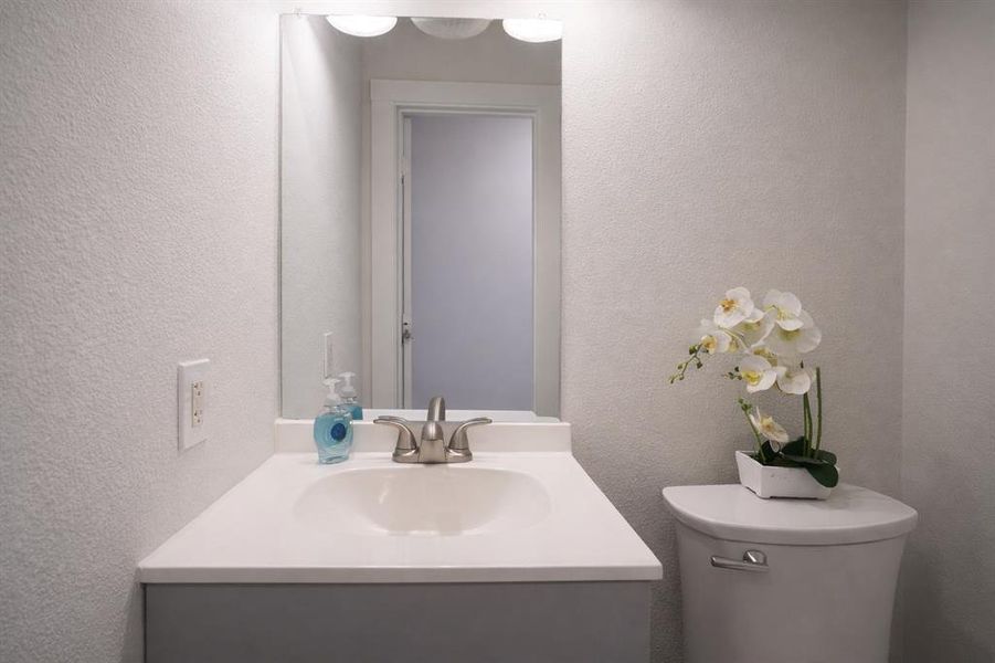 Half bathroom with a textured wall and vanity