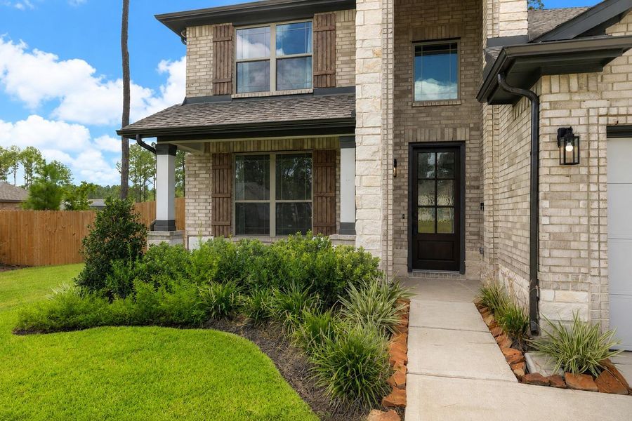 Charming brick exterior with rustic shutters and a welcoming front entrance, complemented by lush landscaping to welcome you home.