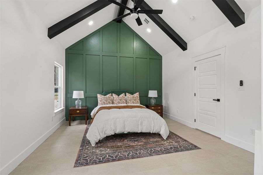 Bedroom featuring visible vents, baseboards, high vaulted ceiling, a decorative wall, and beam ceiling