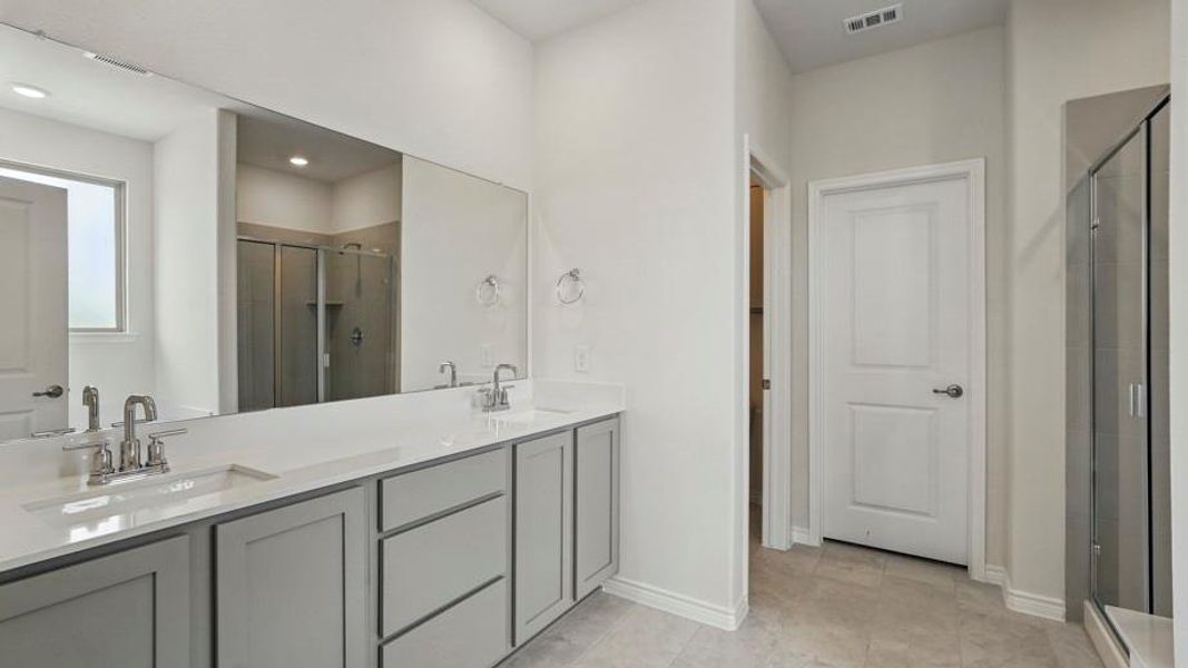 Full bathroom featuring double vanity and a stall shower