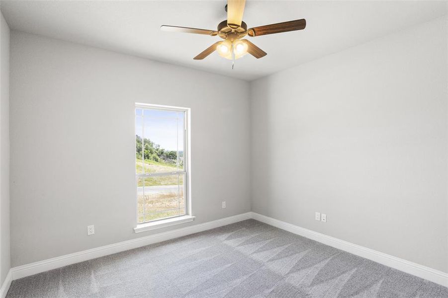 Carpeted spare room featuring ceiling fan