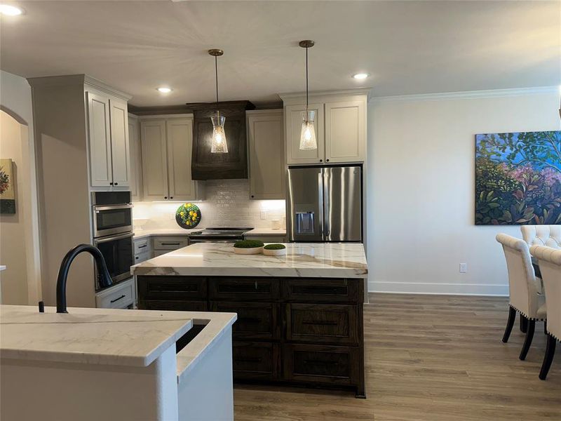 Modern kitchen featuring a large central island with a stone countertop and dark wood cabinetry