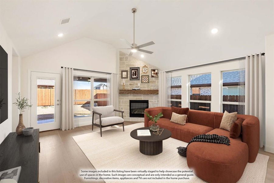 Living room with vaulted ceiling, stone fireplace, ceiling fan, and large windows with backyard views Living room with vaulted ceiling, stone fireplace, ceiling fan, and large windows with backyard views