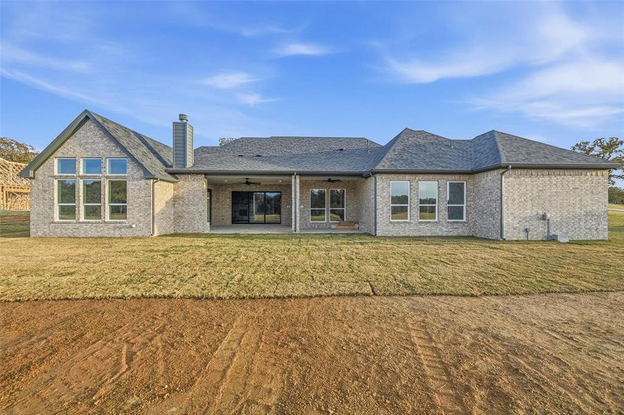 Back of property with a patio, a yard, brick siding, a chimney, and ceiling fan Back of property with a patio, a yard, brick siding, a chimney, and ceiling fan