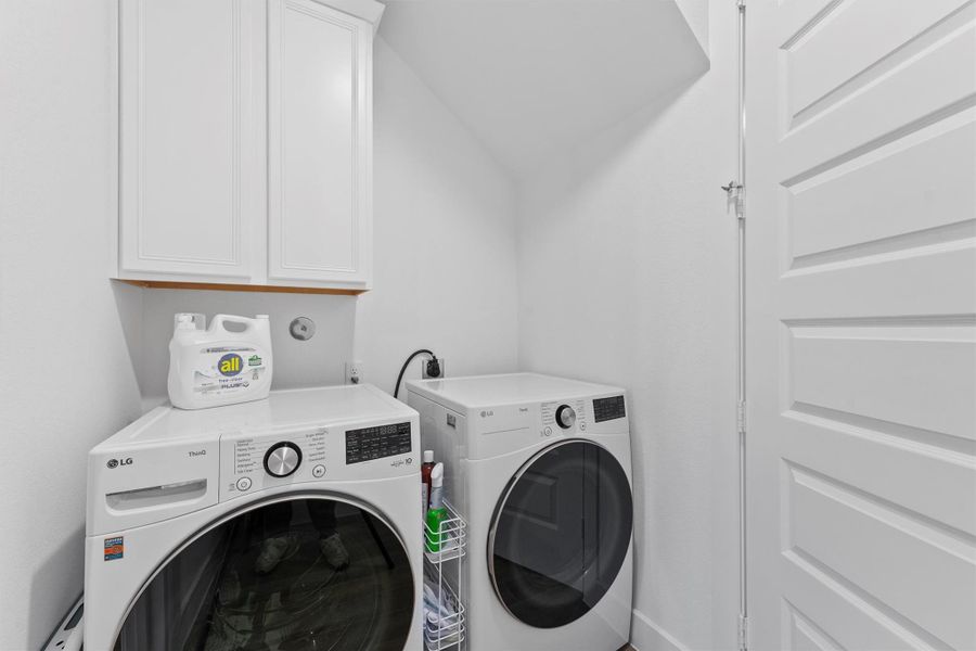 The dedicated laundry room is conveniently located and includes overhead cabinets for storage. It is equipped with connections for both a washer and a gas dryer.