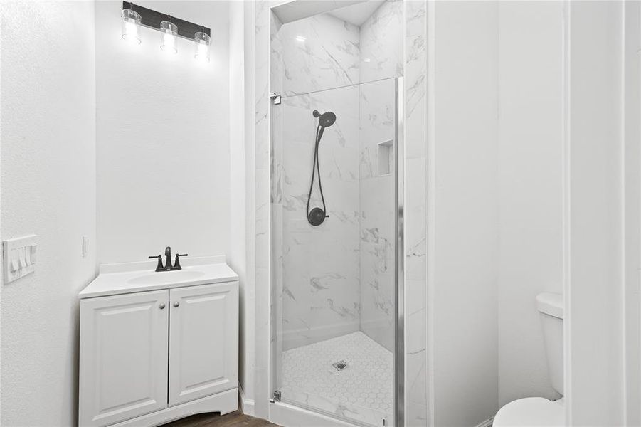 Bathroom featuring toilet, vanity, and a tile shower