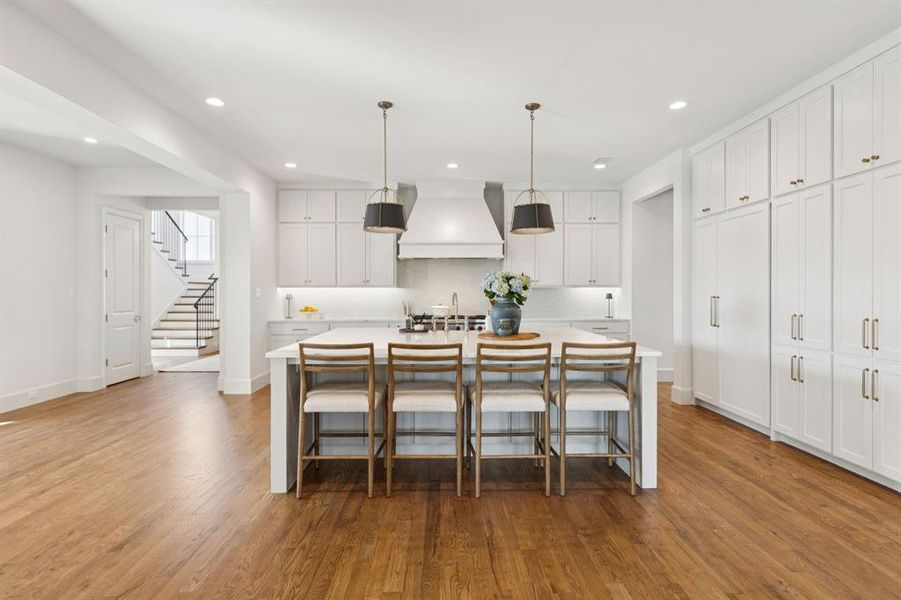 Kitchen featuring a breakfast bar area, white cabinets, hanging light fixtures, an island with sink, and recessed lighting Kitchen featuring a breakfast bar area, white cabinets, hanging light fixtures, an island with sink, and recessed lighting