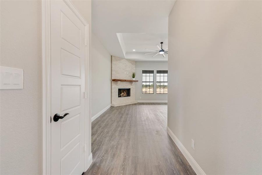 Hallway with a raised ceiling, hardwood / wood-style floors, and brick wall