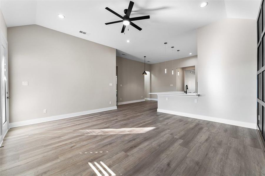 Unfurnished living room featuring lofted ceiling, hardwood / wood-style floors, sink, and ceiling fan