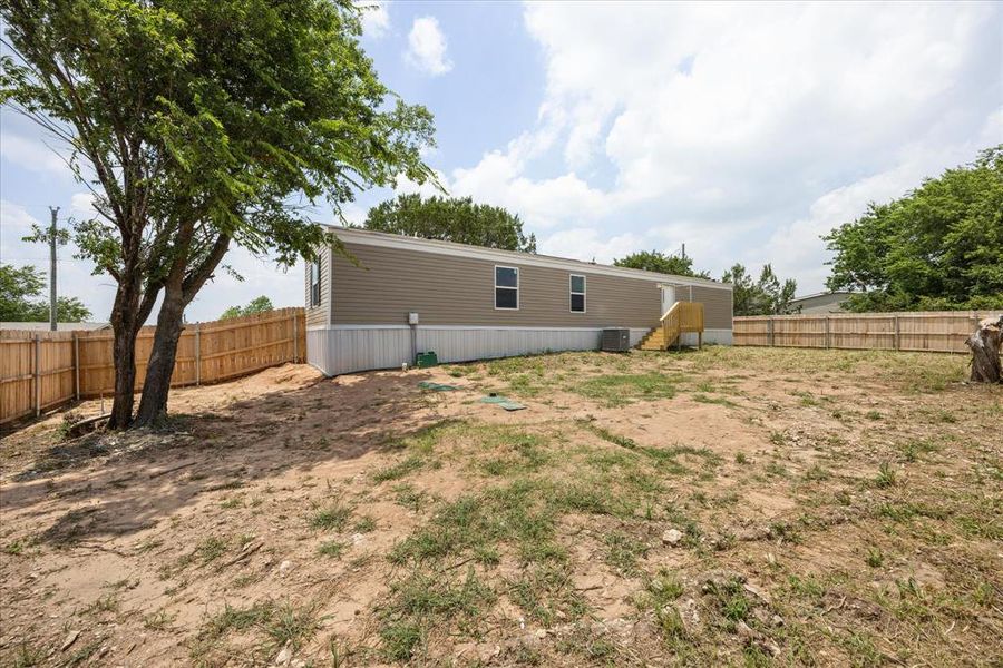 Spacious backyard featuring a new wooden privacy fence and mature trees