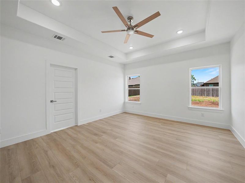 Spacious interior room featuring a tray ceiling with recessed lighting and a ceiling fan Spacious interior room featuring a tray ceiling with recessed lighting and a ceiling fan