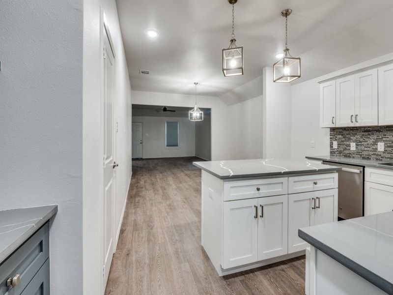 Kitchen with light wood-type flooring, white cabinetry, dishwasher, and decorative backsplash