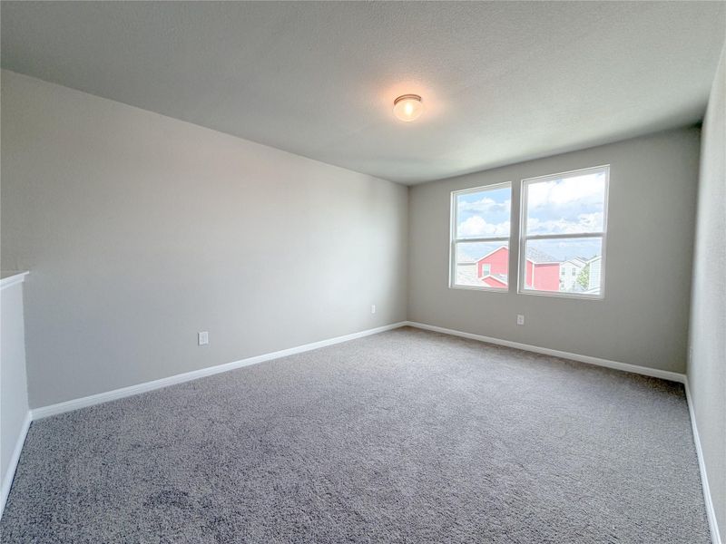 Spacious room featuring gray carpeted flooring, light gray wall paint, and white baseboards