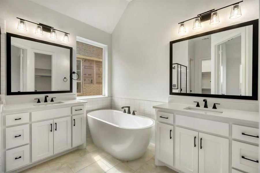 Bathroom with a freestanding tub, tile walls, two vanities, a walk in closet, and wainscoting