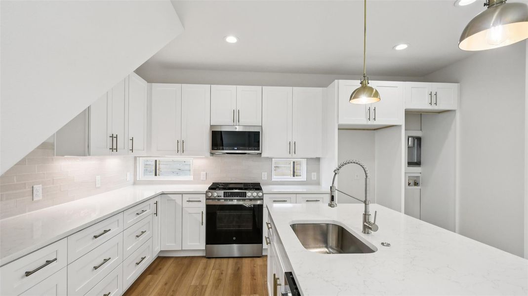 Kitchen with stainless steel appliances, white cabinets, decorative light fixtures, tasteful backsplash, and recessed lighting Kitchen with stainless steel appliances, white cabinets, decorative light fixtures, tasteful backsplash, and recessed lighting